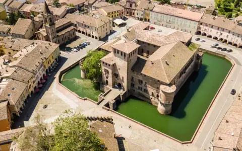 Castello con fossato e borgo storico. Un'idea di cosa vedere a Parma in un giorno, tra torri e tetti rossi.