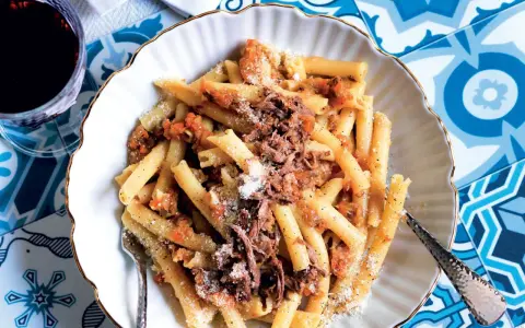 Un piatto invitante di pasta alla genovese, con maccheroni conditi con un ricco ragù di carne e spolverata di parmigiano.