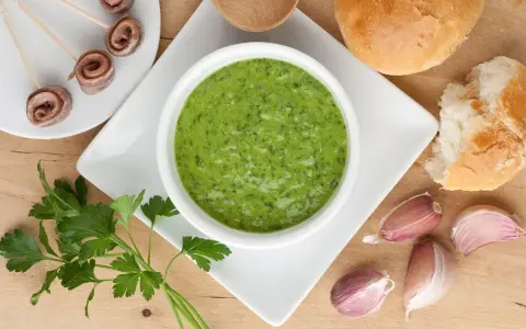 Salsa verde ricetta: prezzemolo fresco, aglio, acciughe arrotolate e pane per accompagnare.