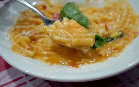 Un cucchiaio di pasta e patate alla napoletana, un piatto cremoso e saporito, con basilico fresco e parmigiano.