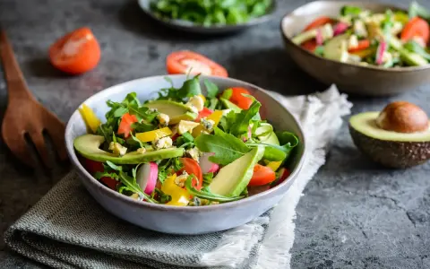 Insalata fresca con avocado, pomodorini, rucola e formaggio blu. Un piatto colorato e salutare.