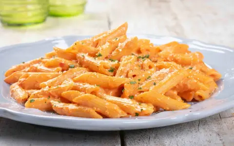 Penne cremose con salsa rosa, un'ottima idea per un pranzo veloce. Spolverata di parmigiano e prezzemolo fresco.