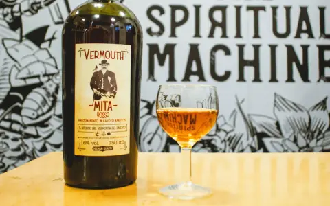 Bottiglia di vermouth rosso Mita e un bicchiere pieno. Scopri come si fa il vermouth con questo aperitivo.