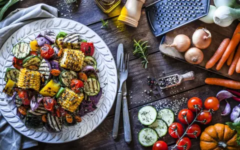 Piatto di contorni di verdure sfiziosi e veloci: zucchine, peperoni, cipolle, pomodorini e pannocchie grigliate, condite con erbe aromatiche.