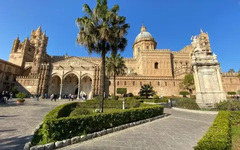 Il percorso per Palermo inizia con la maestosa Cattedrale, tra palme e giardini curati, sotto un cielo azzurro.