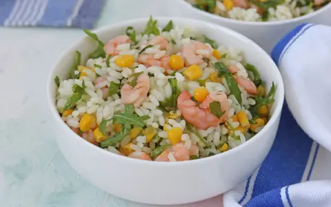 Insalata di riso con gamberetti, mais e rucola, un piatto fresco e colorato, servito in una ciotola bianca.