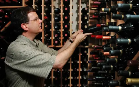 Uomo in cantina sceglie una bottiglia, pensando se il suo chardonnay è fermo o frizzante.
