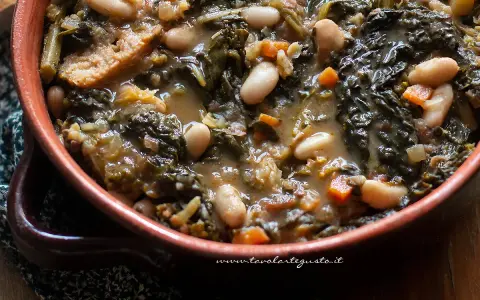 Un piatto fumante di ribollita toscana, con fagioli cannellini, cavolo nero e pane raffermo in un'autentica ciotola di terracotta.