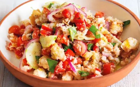 Panzanella ricetta: un'insalata estiva con pane raffermo, pomodori, cetrioli, cipolla rossa e basilico, condita con olio d'oliva.