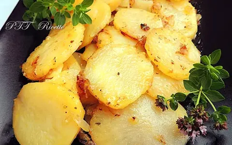Patate e cipolle in padella, dorate e profumate, guarnite con rametti di origano fresco.