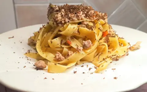 Tagliatelle al ragù con scaglie di tartufo nero, un piatto ricco e profumato, pronto per essere gustato.