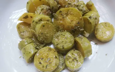 Zucchine trombetta cotte al forno, condite con erbe aromatiche e olio. Un contorno saporito e leggero.
