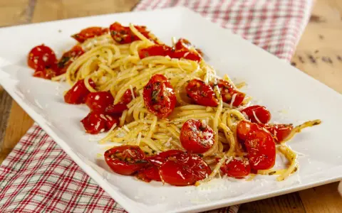 Spaghetti con pomodori al forno alla pugliese, un piatto semplice e gustoso, con pomodorini dolci e profumati.