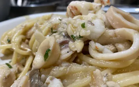 Spaghetti con sugo di pesce, ricchi di calamari e gamberi, un piatto che profuma di mare.