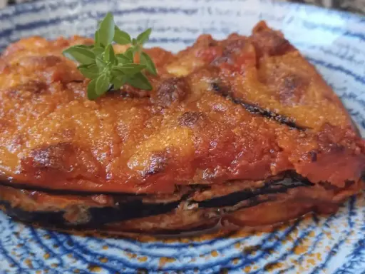Parmigiana in padella, uno strato di melanzane fritte, pomodoro e formaggio, guarnita con basilico fresco.