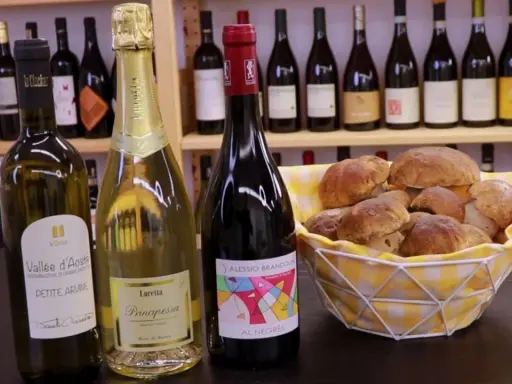 Vino da abbinare ai funghi: una bottiglia di rosso e due spumanti con un cesto di funghi porcini freschi.