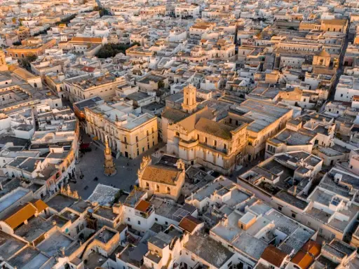 Nardò, dove si trova questo centro storico con chiese barocche e tetti bianchi, illuminato dalla luce dorata del tramonto.