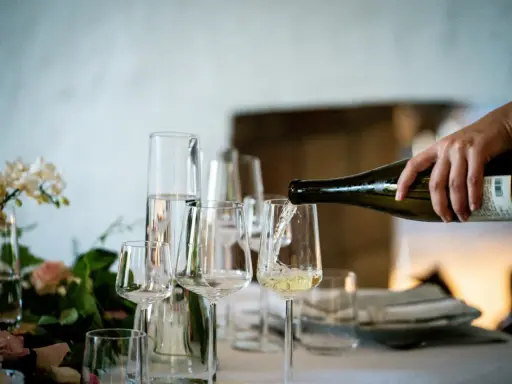 Versando vino bianco in un calice, un assaggio dei profumi dei vitigni siciliani.