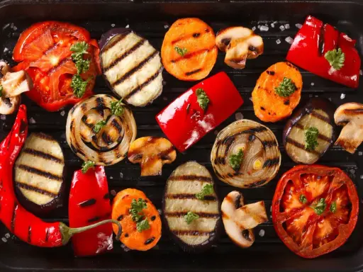 Grigliata di giugno con verdure di stagione: pomodori, melanzane, peperoni, cipolle, carote e funghi, guarnite con prezzemolo.