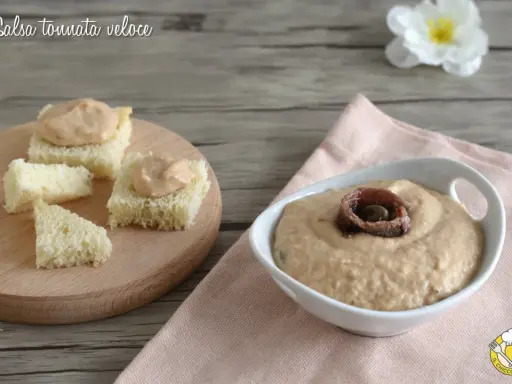Salsa tonnata con maionese, cremosa e gustosa, servita su cubetti di pane e in una ciotola con acciughe.