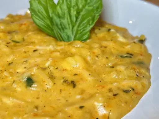 Un cremoso piatto di pasta patate e provola, arricchito da erbe aromatiche e guarnito con una foglia di basilico fresco.