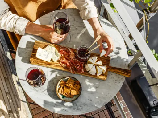 Un tagliere con formaggi, salumi e marmellata, accompagnato da un bicchiere di vino rosso. Le caratteristiche del nebbiolo vino si esaltano con questi sapori.