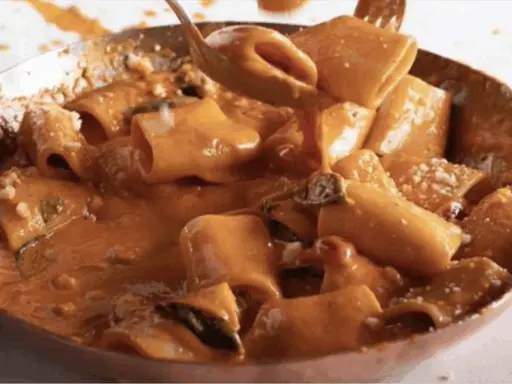Un primo piatto cremoso e invitante: paccheri alla Vittorio, ricoperti da una salsa ricca e profumata, con un tocco di parmigiano.