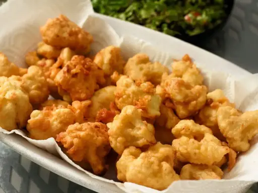 Un piatto colmo di croccante cavolfiore fritto, dorato e invitante, pronto per essere gustato.