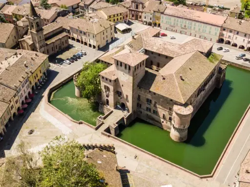 Castello con fossato e borgo storico. Un'idea di cosa vedere a Parma in un giorno, tra torri e tetti rossi.