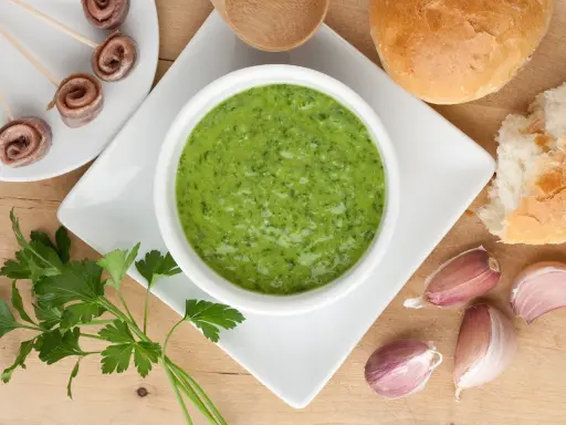 Salsa verde ricetta: prezzemolo fresco, aglio, acciughe arrotolate e pane per accompagnare.