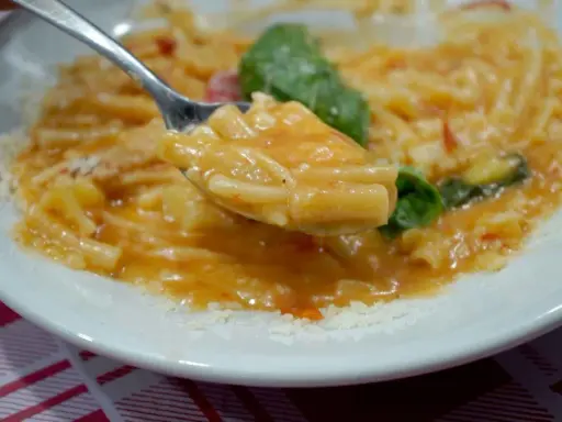 Un cucchiaio di pasta e patate alla napoletana, un piatto cremoso e saporito, con basilico fresco e parmigiano.