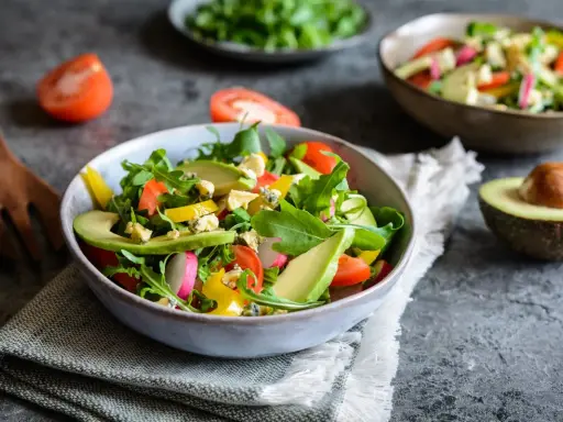 Insalata fresca con avocado, pomodorini, rucola e formaggio blu. Un piatto colorato e salutare.