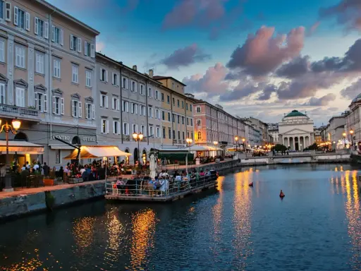 Canale di Trieste al tramonto, con ristoranti sul lungomare e riflessi dorati sull'acqua. Un'ottima idea per una delle città da visitare in un giorno.