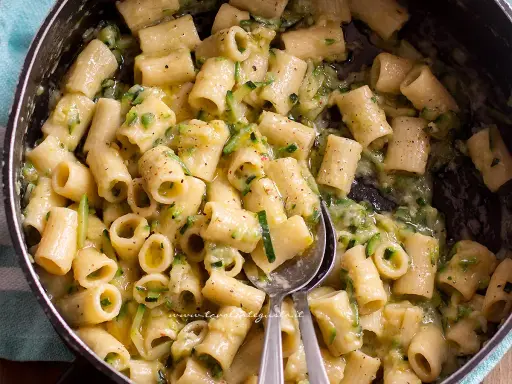 Primo piatto di pasta con pancetta e zucchine, condito con una crema saporita e pepe nero.