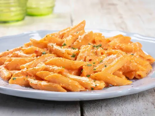 Penne cremose con salsa rosa, un'ottima idea per un pranzo veloce. Spolverata di parmigiano e prezzemolo fresco.