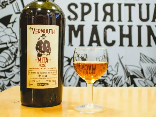 Bottiglia di vermouth rosso Mita e un bicchiere pieno. Scopri come si fa il vermouth con questo aperitivo.