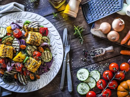 Piatto di contorni di verdure sfiziosi e veloci: zucchine, peperoni, cipolle, pomodorini e pannocchie grigliate, condite con erbe aromatiche.