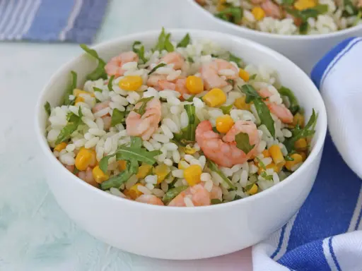 Insalata di riso con gamberetti, mais e rucola, un piatto fresco e colorato, servito in una ciotola bianca.