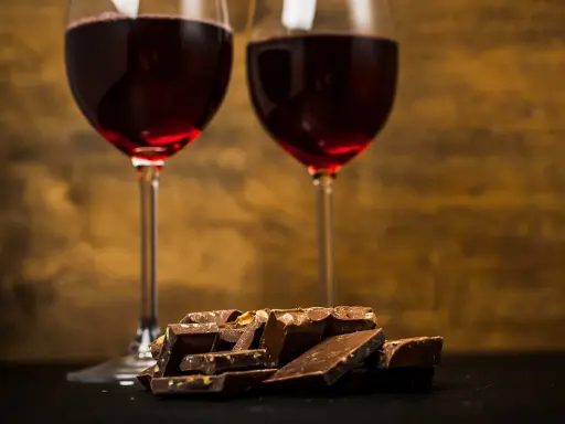 Due calici di vino rosso e una pila di cioccolato fondente, un perfetto abbinamento vino e cioccolato per un momento di piacere.