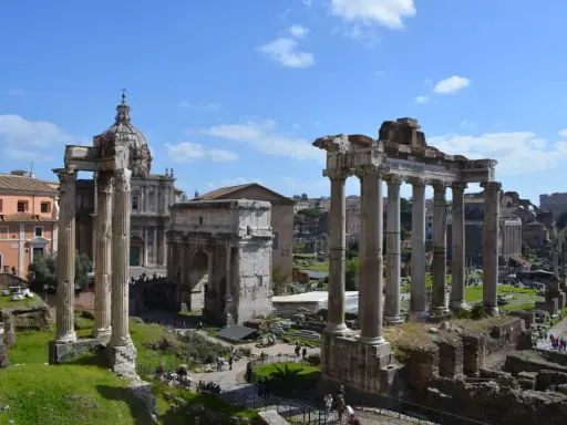 Antiche rovine romane, un arco trionfale e una chiesa con cupola, ideali per scoprire cosa fare a Roma nel weekend.