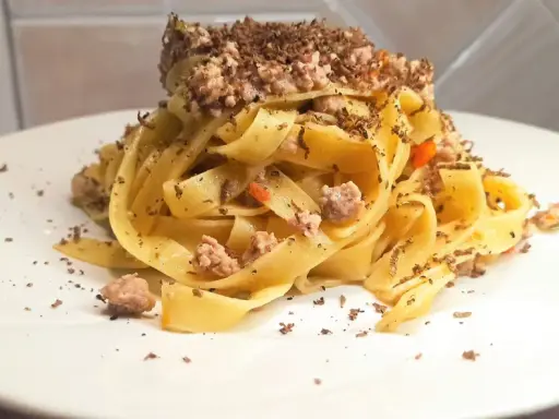 Tagliatelle al ragù con scaglie di tartufo nero, un piatto ricco e profumato, pronto per essere gustato.