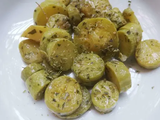Zucchine trombetta cotte al forno, condite con erbe aromatiche e olio. Un contorno saporito e leggero.