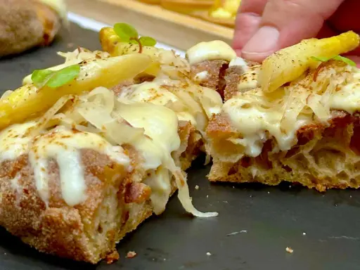 Pizza in padellino con formaggio filante, patate croccanti e un tocco di verde. Una delizia da gustare.