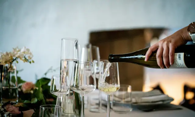 Versando vino bianco in un calice, un assaggio dei profumi dei vitigni siciliani.