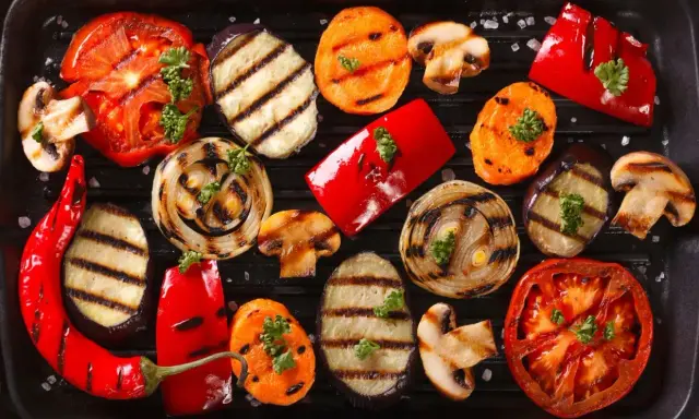 Grigliata di giugno con verdure di stagione: pomodori, melanzane, peperoni, cipolle, carote e funghi, guarnite con prezzemolo.