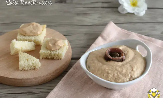 Salsa tonnata con maionese, cremosa e gustosa, servita su cubetti di pane e in una ciotola con acciughe.