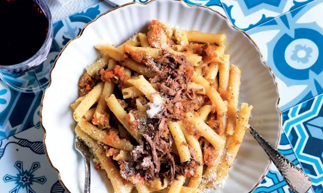 Un piatto invitante di pasta alla genovese, con maccheroni conditi con un ricco ragù di carne e spolverata di parmigiano.