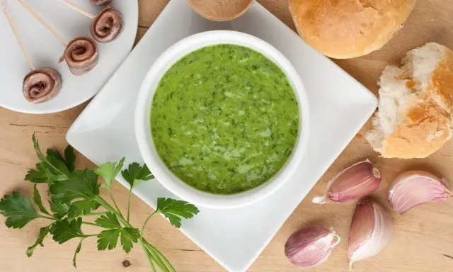 Salsa verde ricetta: prezzemolo fresco, aglio, acciughe arrotolate e pane per accompagnare.
