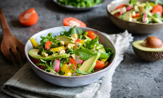 Insalata fresca con avocado, pomodorini, rucola e formaggio blu. Un piatto colorato e salutare.