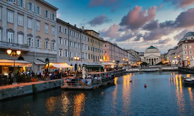 Canale di Trieste al tramonto, con ristoranti sul lungomare e riflessi dorati sull'acqua. Un'ottima idea per una delle città da visitare in un giorno.